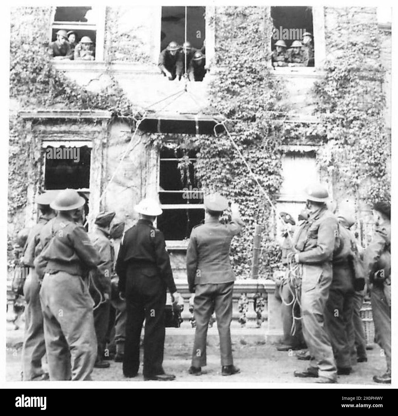 Armee-Truppen trainiert, um einen Unfall aus einem Fenster mit einer horizontalen Bahre zu senken. Fotografisches negativ von der britischen Armee. Stockfoto