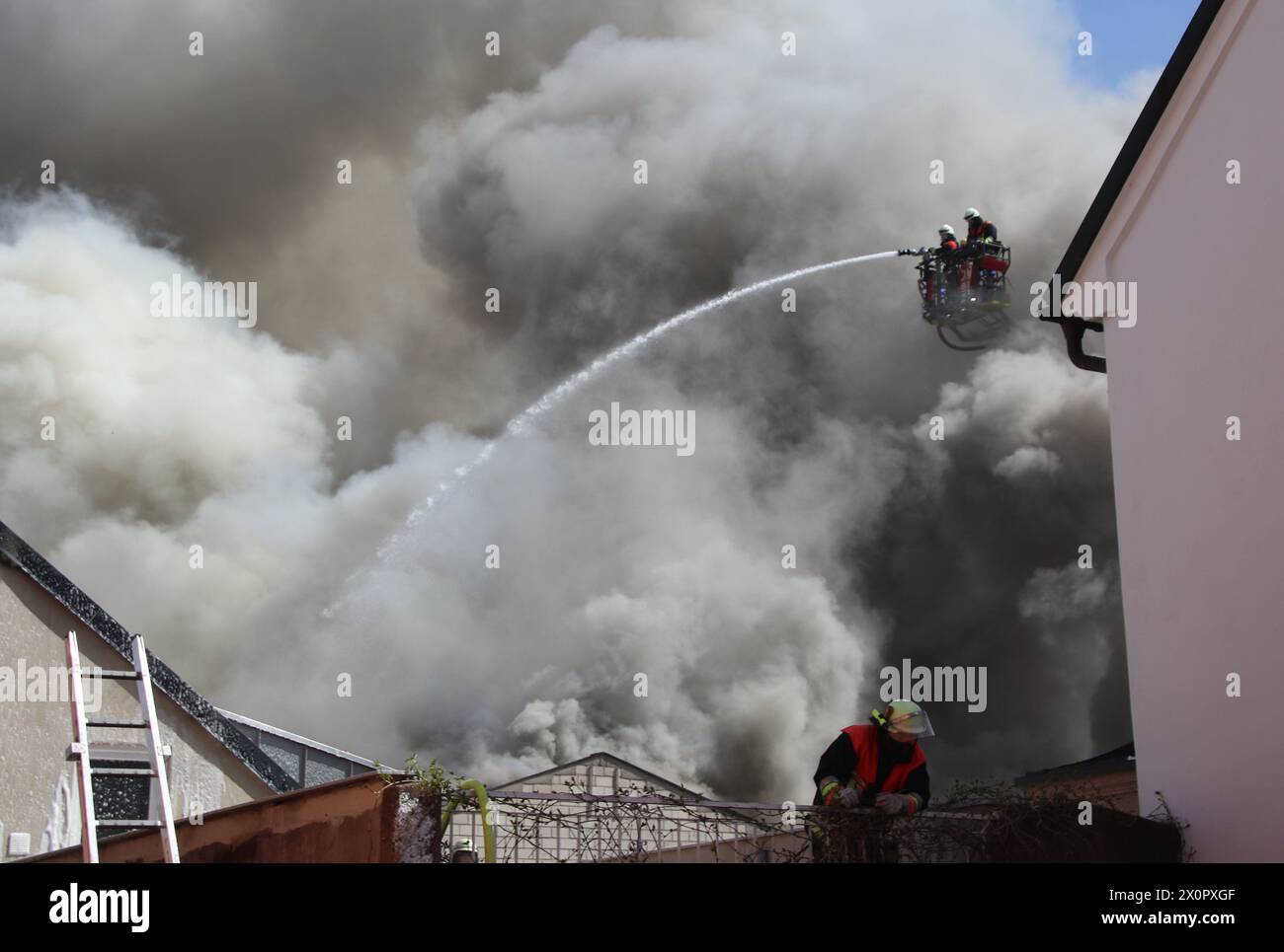 Auerbach I.D.Oberpfalz, Deutschland. April 2024. Die Feuerwehr versucht, den Brand im Dachstuhl eines Lagers zu löschen, der sich teilweise auf benachbarte Gebäude ausbreitet. Fünf Gebäude waren von dem Brand betroffen und der Schaden dürfte in der hohen sechsstelligen Reichweite liegen, sagte ein Polizeisprecher. Zwei Personen wurden ebenfalls leicht durch Rauch verletzt. Quelle: Masching/NEWS5/dpa/Alamy Live News Stockfoto