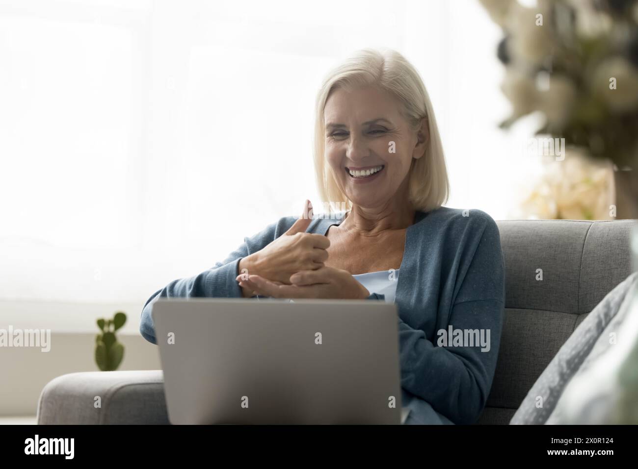 Reife Frau mit Hörbeeinträchtigung nehmen an einem virtuellen Treffen Teil Stockfoto