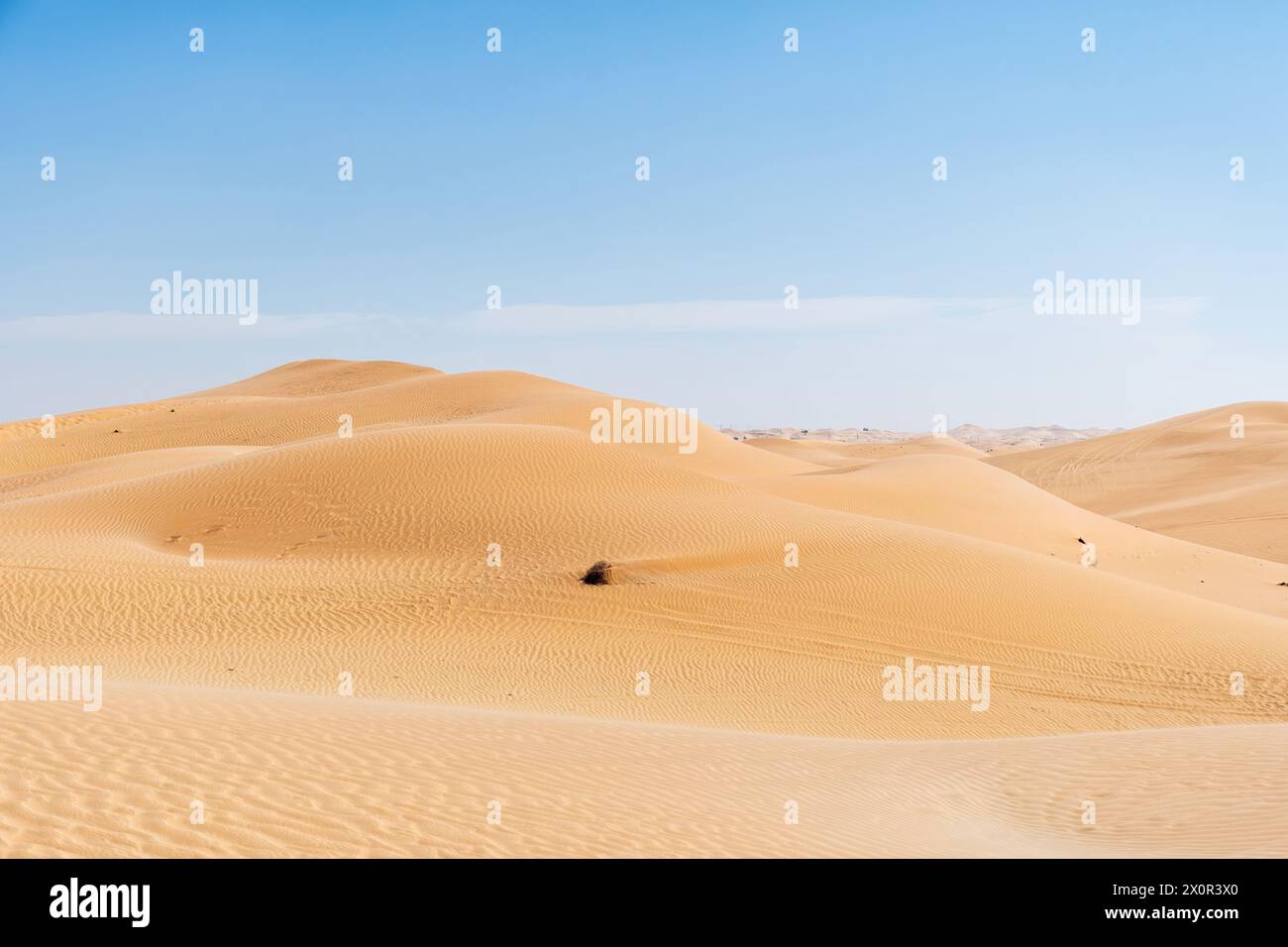 Weite Wüstensanddüne mit Hügeln und blauem Himmel. Wellige Sandmuster. Abstrakte Landschaftshintergründe Stockfoto