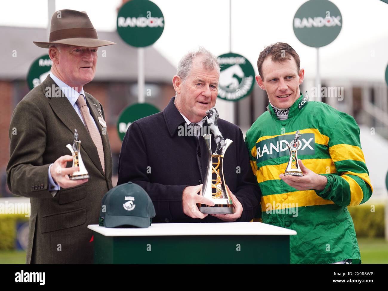 Trainer Willie Mullins, Eigentümer J. P. McManus und Jockey Paul Townend mit der Trophäe, nachdem sie am dritten Tag des Randox Grand National Festival 2024 auf der Aintree Racecourse, Liverpool, die Randox Grand National Handicap Chase mit I am Maximus gewonnen hatten. Bilddatum: Samstag, 13. April 2024. Stockfoto