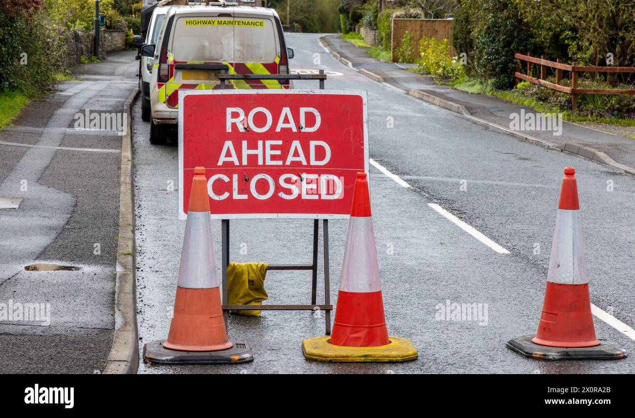 Schild „Road Ahead Closed“ (Straße vor geschlossen) mit Highway Maintenance-Van – Metallweiß auf rotem Text Stockfoto