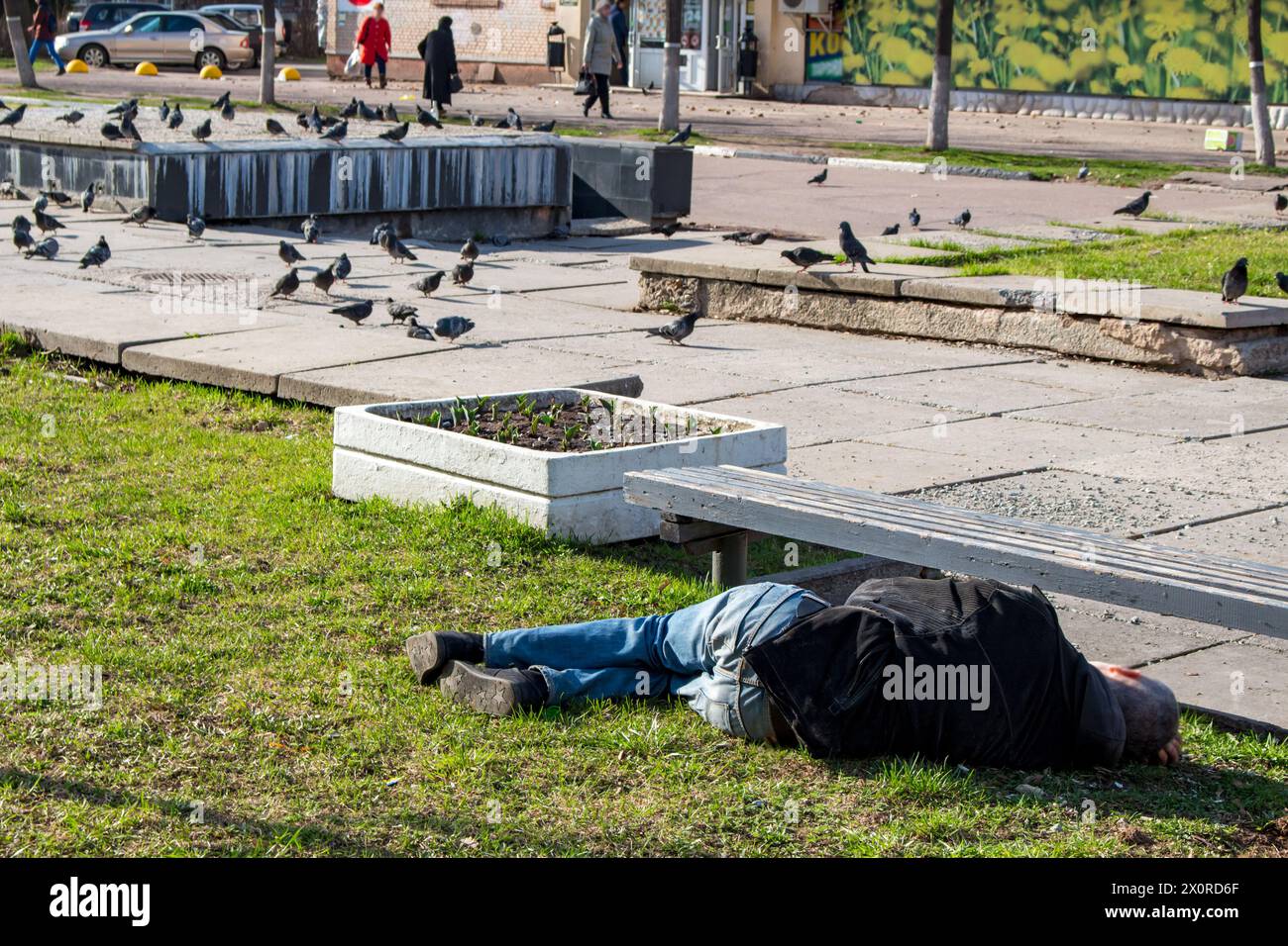 Ein betrunkener Mann schläft auf dem Gras in der Stadt Stockfoto