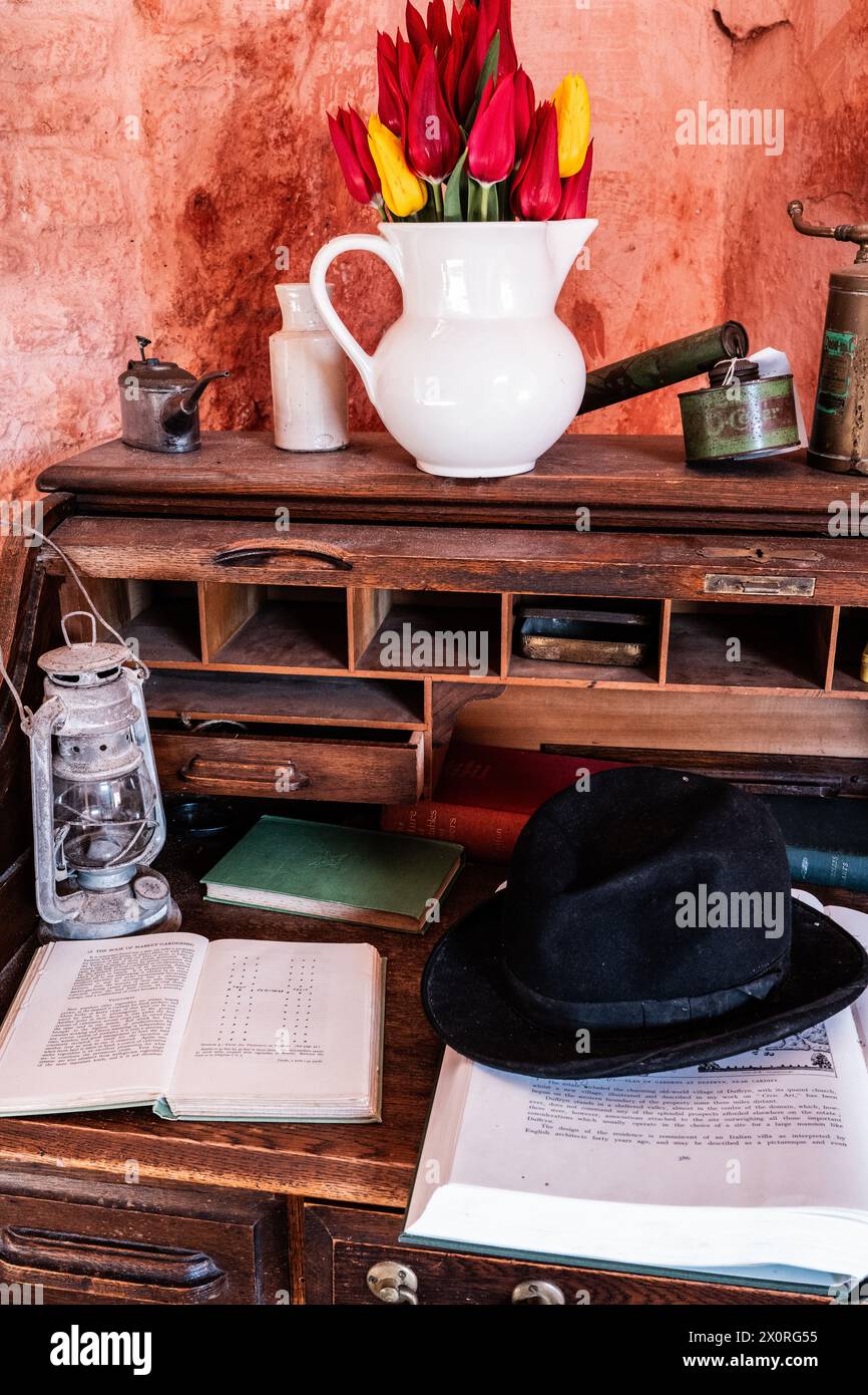 Eine antike Hurrikanlampe, Bowler Hut, weiße Vase, französische Tabakdose, offene Bücher und Messingspritzen auf einem altmodischen Holzbüro. Retro-Style. Stockfoto