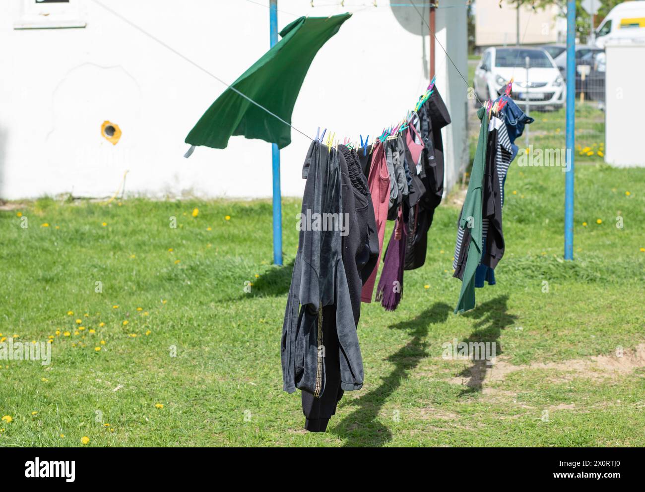 Wäschetrocknung an einer Schnur zwischen Blockhäusern. Die ersten sonnigen und windigen Frühlingstage. Stockfoto