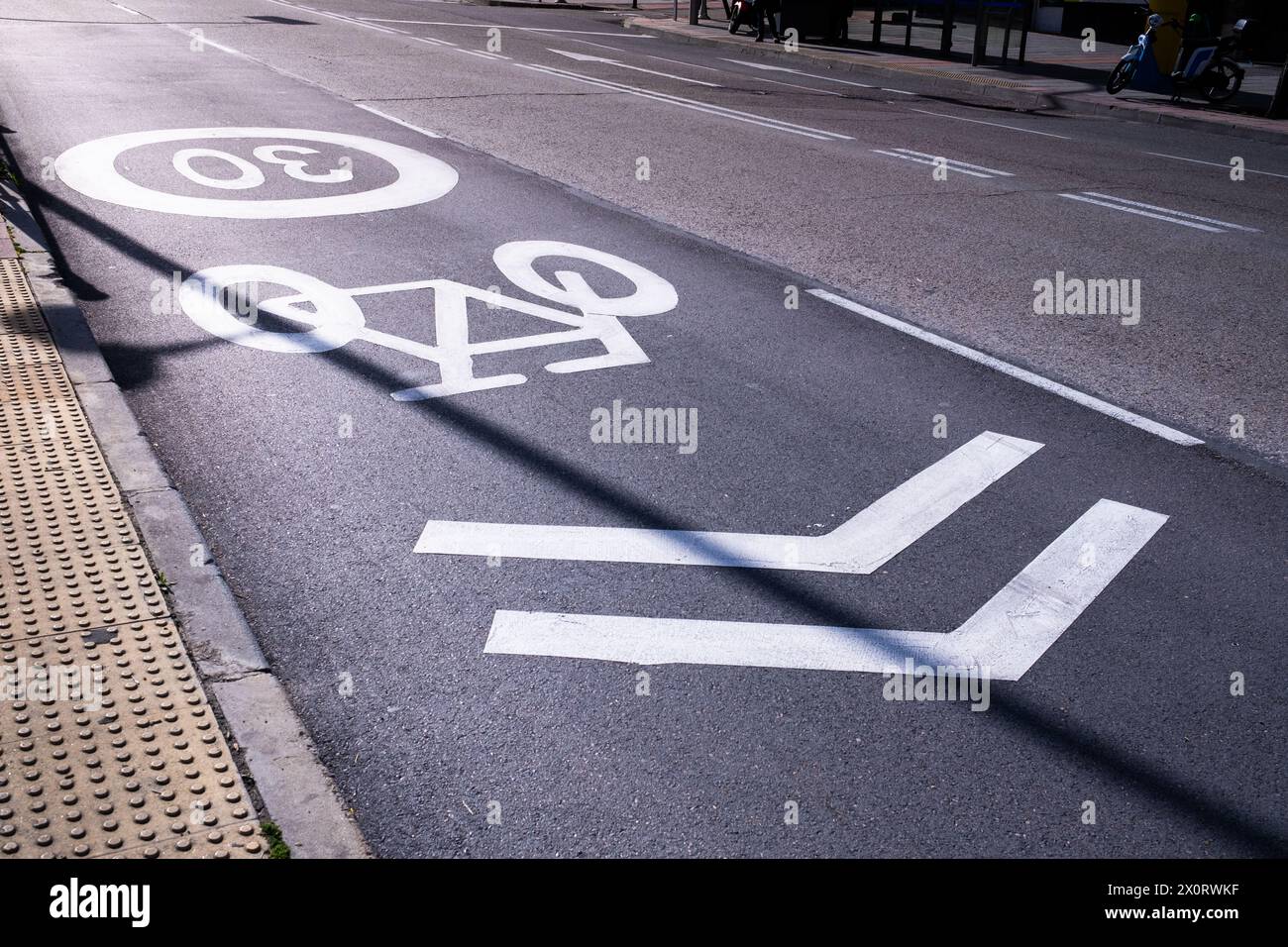 Ein Radweg im Herzen der Stadt gepflastert und abgegrenzt. Es gibt Schilder, die die Geschwindigkeit auf 30 km/h und die Zirkulationsrichtung beschränken. Sonnenaufgang Stockfoto