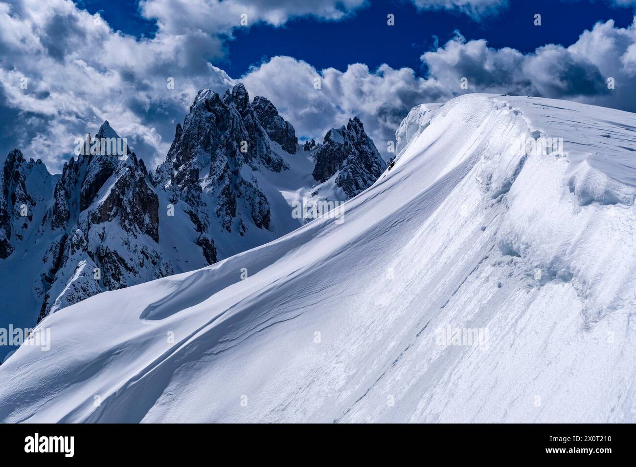Schneeschwankungen schaffen kunstvolle Strukturen im Naturpark Tre Cime im Winter, die Gipfel von Cadini di Misurina in der Ferne, vom Monte Campedele aus gesehen. Stockfoto