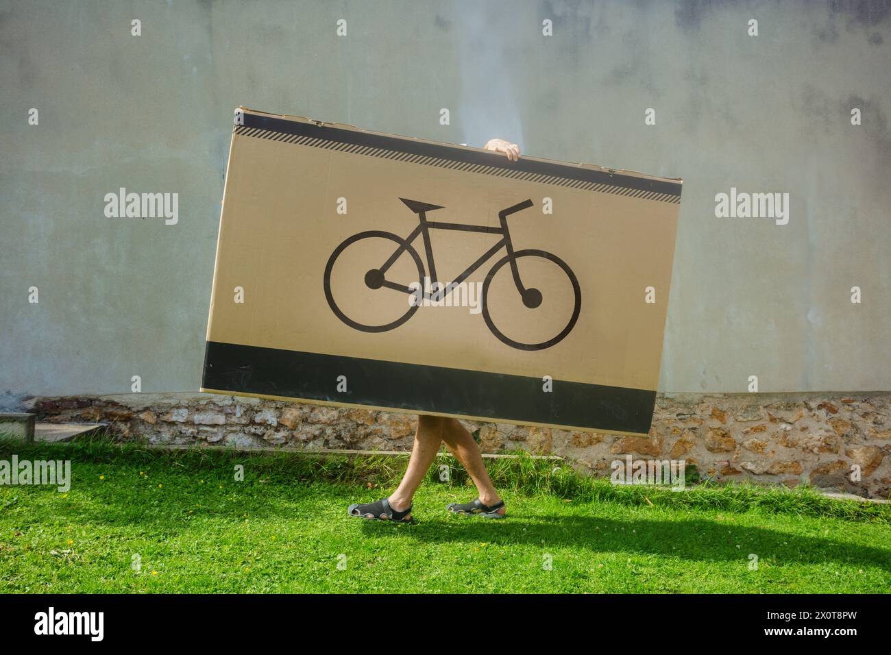 Eine Person versteckt sich und trägt eine riesige Box mit einem Fahrrad-Logo Stockfoto