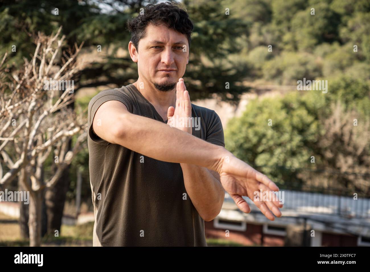Ein Mann mittleren Alters trainiert in Kung Fu, einer chinesischen Kampfkunst, draußen. Er konzentriert sich auf die Verfeinerung seiner Fähigkeiten und Techniken in der natürlichen Umgebung Stockfoto