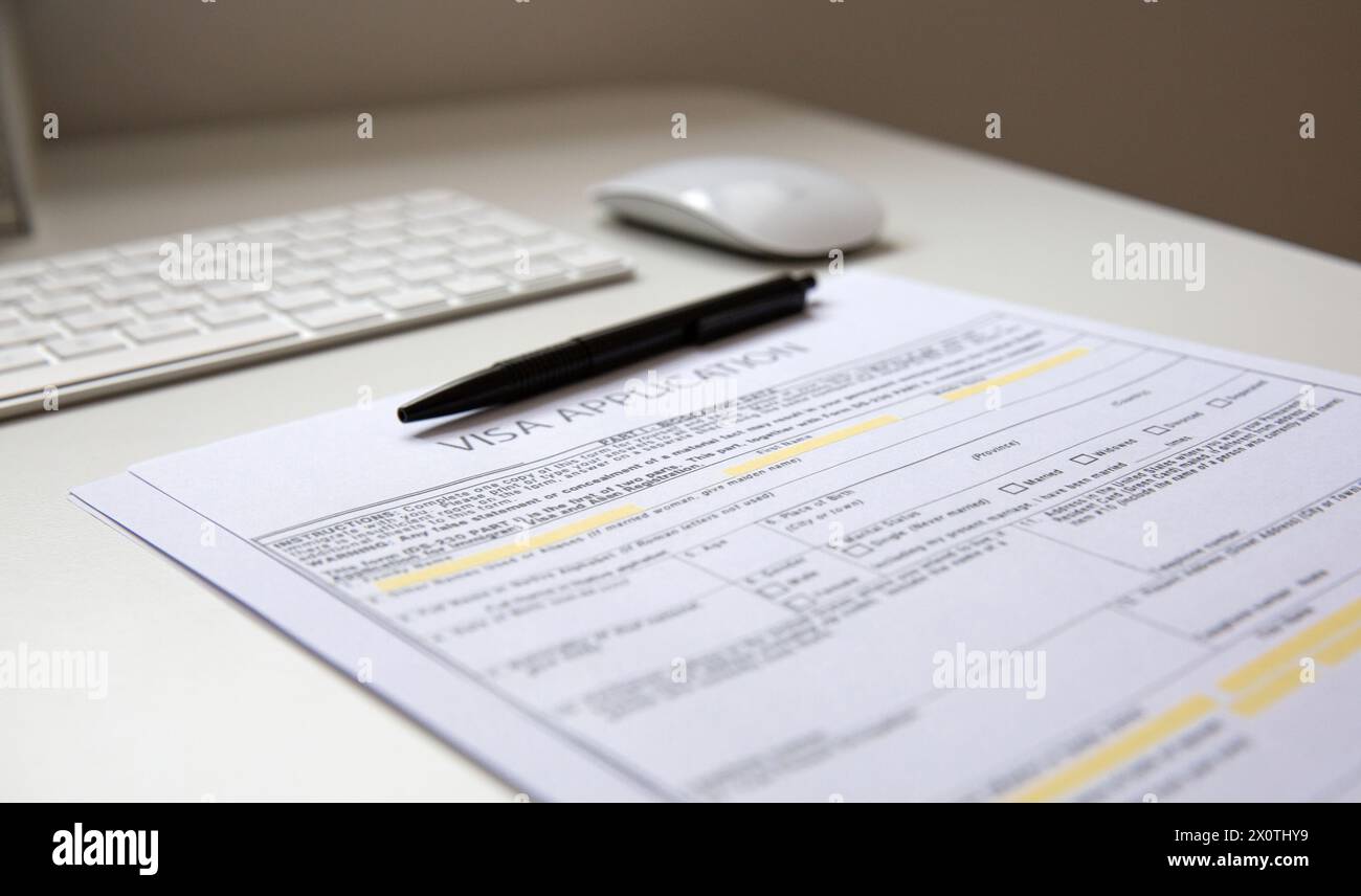 Nahaufnahme einer schwarzen Panne auf dem Visumantragsdokument, auf dem Tisch mit Computertastatur und Maus Stockfoto