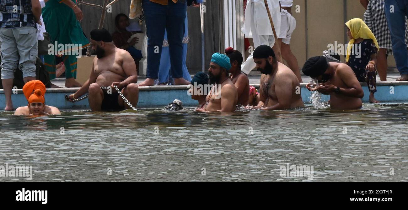 NEW DELHI, INDIEN - 13. APRIL: Gläubige nehmen ein Bad im heiligen Teich von Gurudwara Bangla Sahib anlässlich des Baisakhi-Festivals am 13. April 2024 in Neu-Delhi, Indien. Baisakhi oder Vaisakhi, ein beliebtes Frühlingsfest, das den ersten Tag des Monats Vaisakh markiert, wird mit viel Enthusiasmus unter den Hindu-, Sikh- und buddhistischen Gemeinschaften gefeiert. Es ist der Beginn des Punjabi und Sikh Neujahrs, das in ganz Indien gefeiert wird, insbesondere in Punjab und Nordindien. Baisakhi wird am 13. April dieses Jahres beobachtet, was den Beginn der Erntesaison in Punjab einläutet. Es fällt auf den ersten Tag von hin Stockfoto