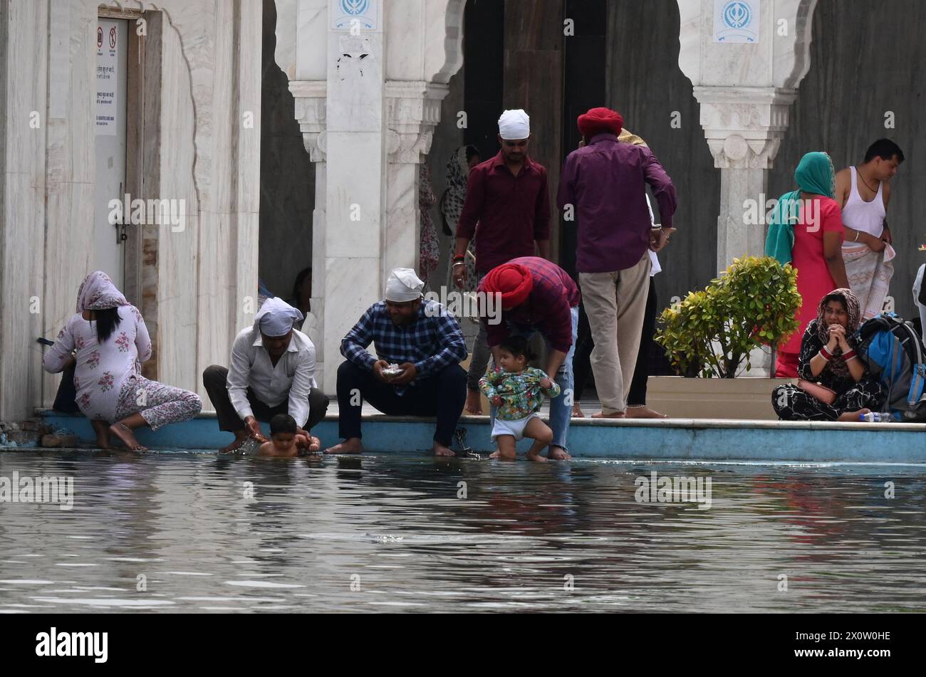 NEW DELHI, INDIEN - 13. APRIL: Gläubige nehmen ein Bad im heiligen Teich von Gurudwara Bangla Sahib anlässlich des Baisakhi-Festivals am 13. April 2024 in Neu-Delhi, Indien. Baisakhi oder Vaisakhi, ein beliebtes Frühlingsfest, das den ersten Tag des Monats Vaisakh markiert, wird mit viel Enthusiasmus unter den Hindu-, Sikh- und buddhistischen Gemeinschaften gefeiert. Es ist der Beginn des Punjabi und Sikh Neujahrs, das in ganz Indien gefeiert wird, insbesondere in Punjab und Nordindien. Baisakhi wird am 13. April dieses Jahres beobachtet, was den Beginn der Erntesaison in Punjab einläutet. Es fällt auf den ersten Tag von hin Stockfoto