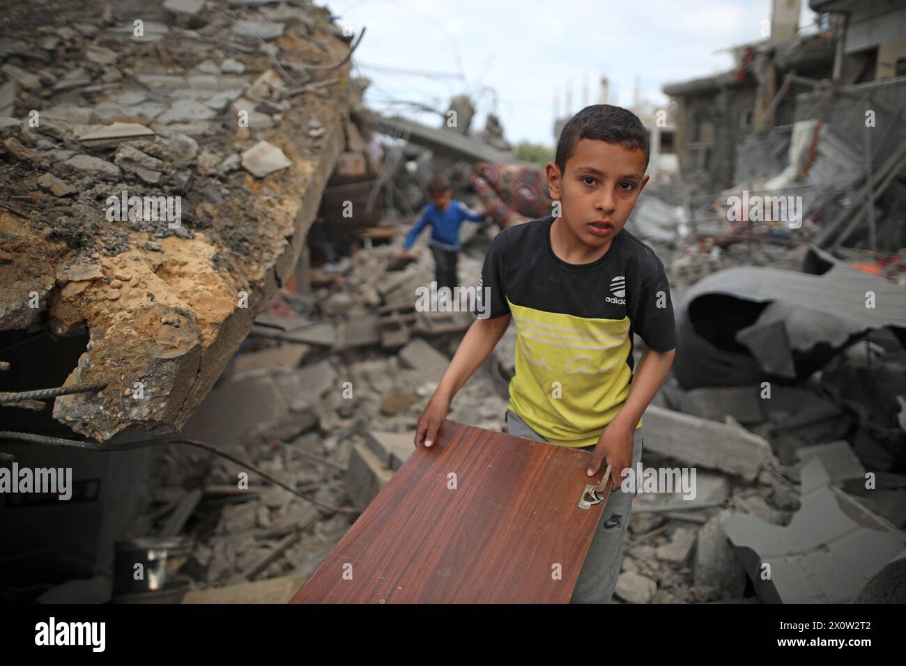 (240414) -- GAZA, 14. April 2024 (Xinhua) -- Ein Junge räumt Trümmer nach israelischen Angriffen auf das Flüchtlingslager Nuseirat im zentralen Gazastreifen, 13. April 2024. Die Islamische Widerstandsbewegung (Hamas) gab am Samstag bekannt, dass sie auf die Vermittler in Ägypten und Katar wegen des geplanten Waffenstillstands im Gazastreifen reagiert und ihre Forderungen bekräftigt hat. Die Hamas wiederholte in der Zwischenzeit ihre Forderungen nach einem dauerhaften Waffenstillstand, dem Abzug aller israelischen Truppen aus dem Gazastreifen, der Rückkehr der vertriebenen Palästinenser in ihre Häuser, der Erleichterung von Hilfsgütern und Hilfsgütern in Gaza und dem Beginn des Wiederaufbaus Stockfoto