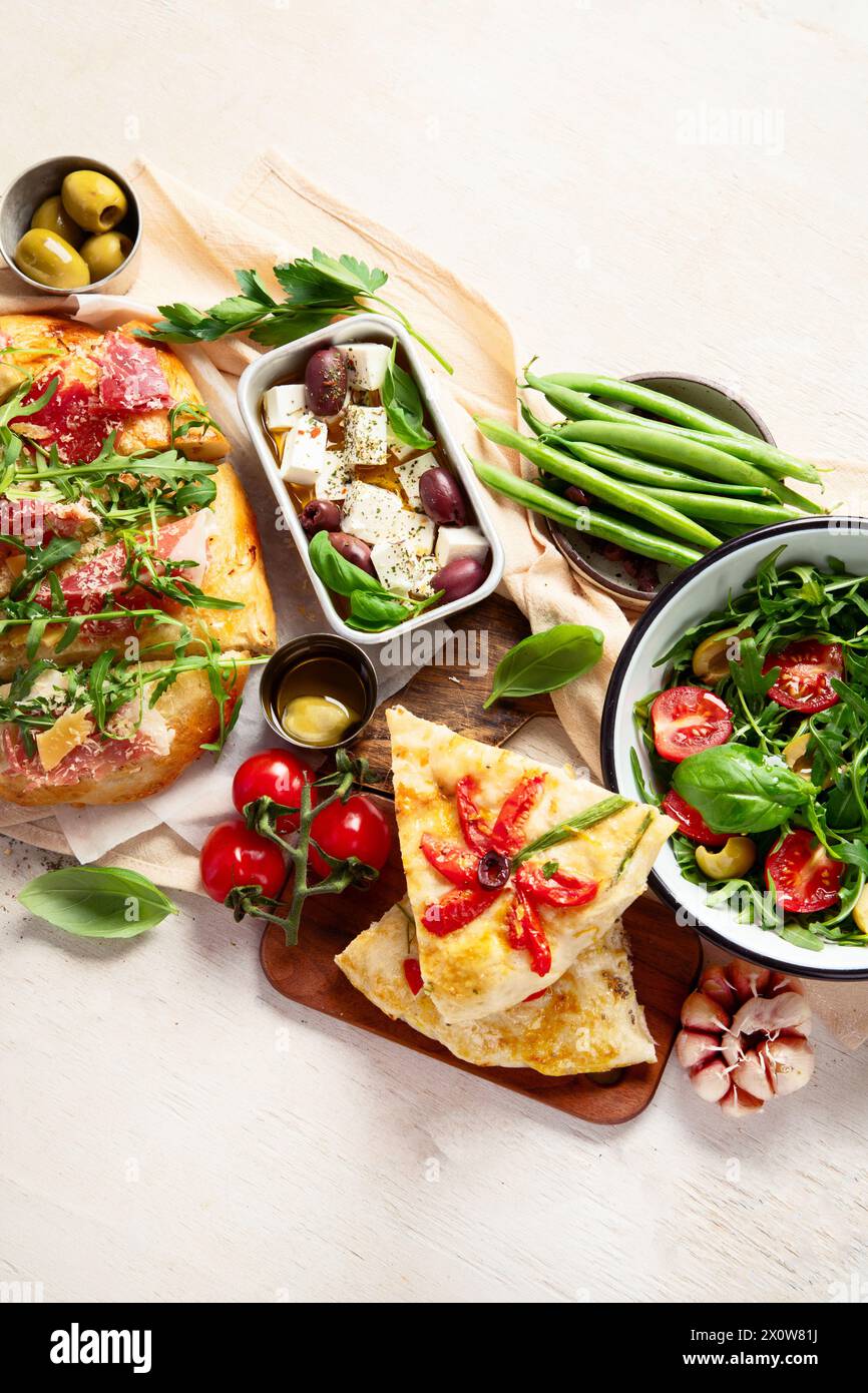 Vollständiger Tisch mit italienischen Gerichten auf Tellern Pizza, Pasta, Ravioli, Salat und Focaccia auf weißem Hintergrund. Draufsicht Stockfoto