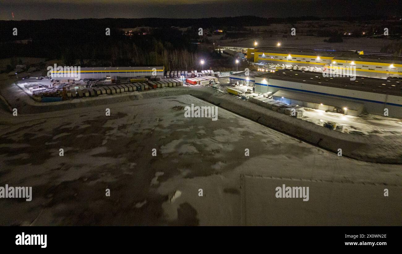 Drohnenfotografie von Logistiklagern und geparkten LKWs während der winterlichen bewölkten Nacht Stockfoto