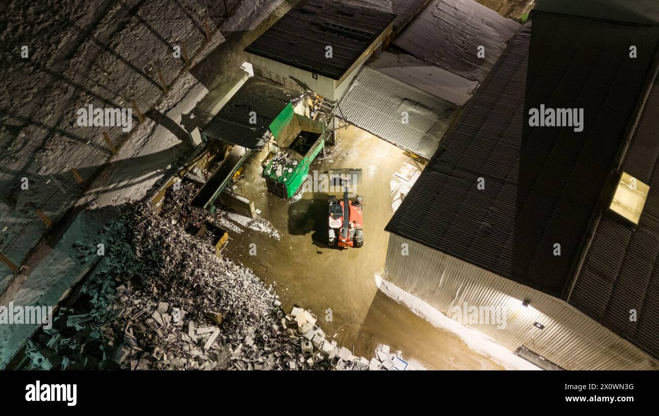 Drohnenfotografie von Metallrecyclinganlagen und Maschinen, die nachts in der winterlichen bewölkten Nacht Metall aussortieren Stockfoto