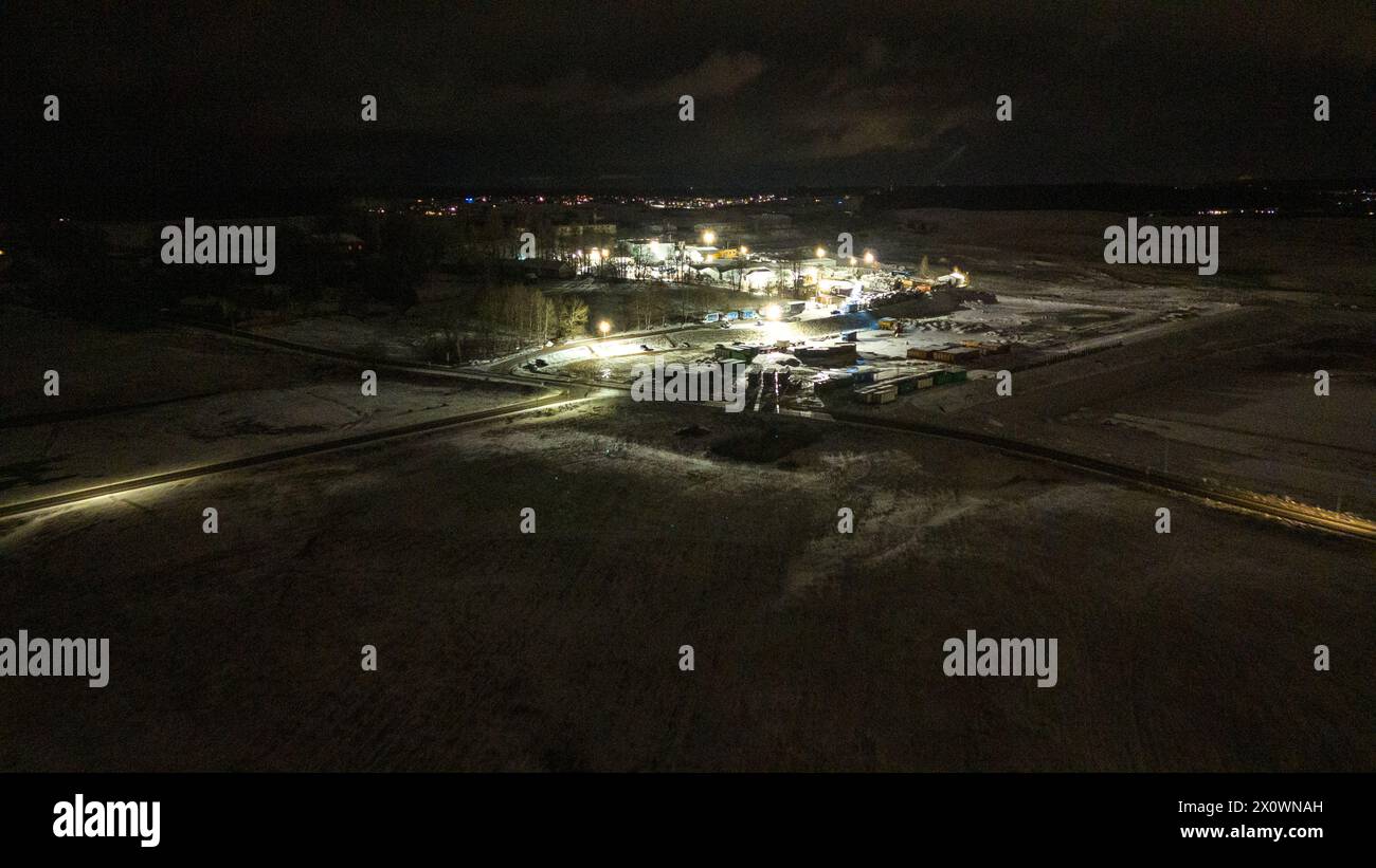 Drohnenfotografie von Metall-Recycling-Anlagen in der Entfernung während der winterlichen bewölkten Nacht Stockfoto