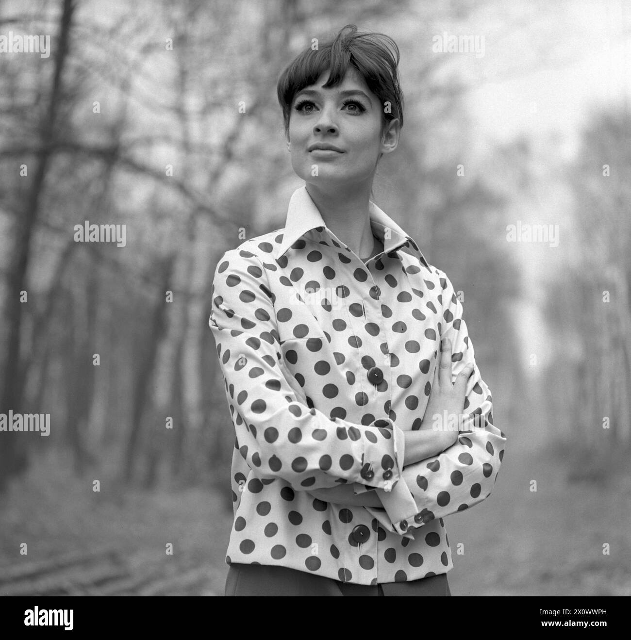 01.03.1971, Berlin, DDR - Werbeaufnahme für Modezeitschriften: Model Show im Wald die neueste Damenmode. 30-40 Jahre, 70er Jahre, Alltag, aussen, Aussenaufnahme, Bekleidung, Berlin, Bluse, Damenmode, DDR, deutsch, Deutsche Demokratische Republik, Deutschland, Europa, europaeisch, Mode, Frau, Fruehjahr, Fruehling, Für Dich, DDR, Gesellschaft, Historie, historisch, Jahreszeit, Kaukasierin, Kaukasisch, Kleidung, Mannequin, Mensch, Modus, Modeaufnahme, Modekollektion, Modell, Modeshooting, modisch, Natur, Person, pmscartandhistory, Pose, posieren, praesentieren, Pramo, QF, Quadrat, Querformat, Stockfoto