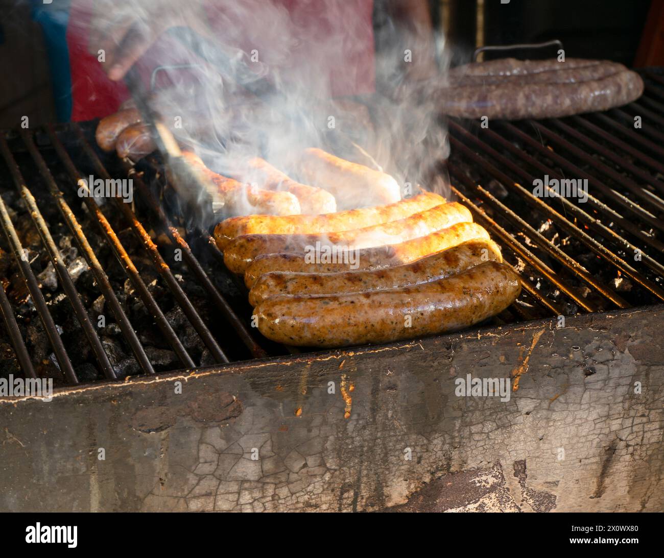 Würstchen, die auf einem rauchigen Grill im Freien gegrillt werden, mit sichtbaren Grillspuren und Aufmerksamkeit auf das heiße Essen in Mexiko Stockfoto