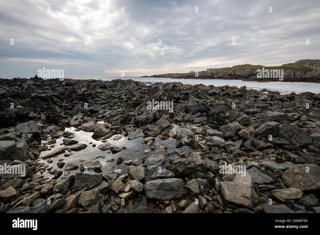 Felsige Küste an der St Cwyfan's Church, Porth Cwyfan bei Aberffraw, Anglesey, Nordwales. Stockfoto