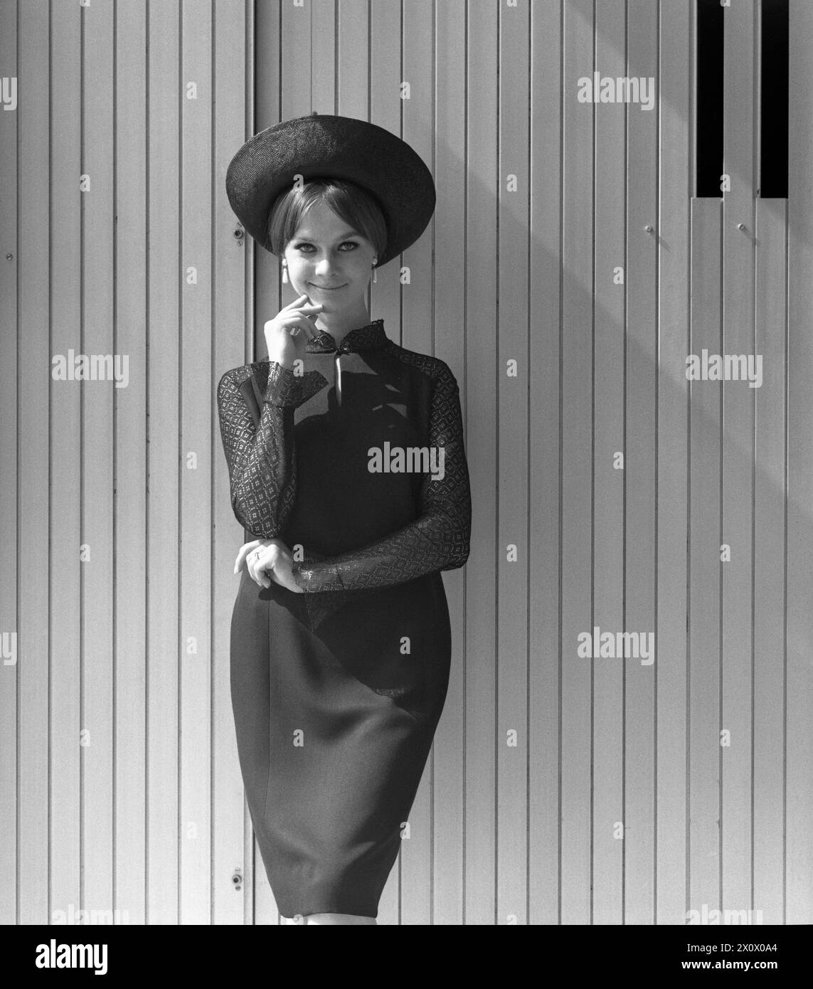 13.07.1971, Berlin, DDR - Werbeaufnahme für Modezeitschriften: Model zeigt die neueste Sommer-Mode. 20-30 Jahre, 70er Jahre, Alltag, aussen, Aussenaufnahme, Bekleidung, Berlin, Blick in die Kamera, Blickkontakt, DDR, deutsch, Deutsche Demokratische Republik, Deutschland, elegant, Eleganz, Europa, europaeisch, Mode, Frau, Freizeit, für dich, DDR, Gesellschaft, Historie, historisch, Hut, Jahreszeit, Kamerablick, Kaukasierin, Kaukasisch, Kleid, Kleidung, Kopfbedeckung, Mensch, Mode, Modeaufnahme, Modekollektion, Modell, Modeshooting, modisch, Person, pmscartandhistory, praesentieren, Pramo, Q Stockfoto