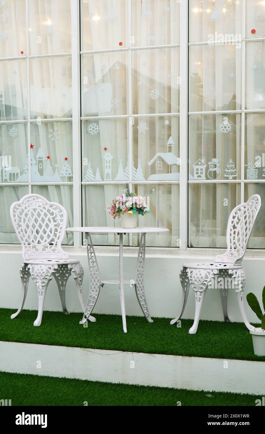 Weißer, schmiedeeiserner Teetisch und Stühle im Hinterhof Stockfoto