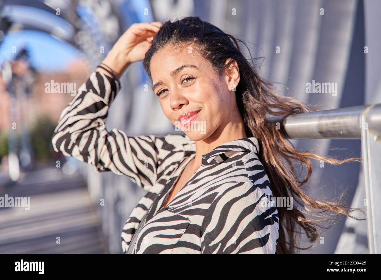 Die junge Latina, die in die Kamera blickt und ihr Haar mit der Hand berührt Stockfoto