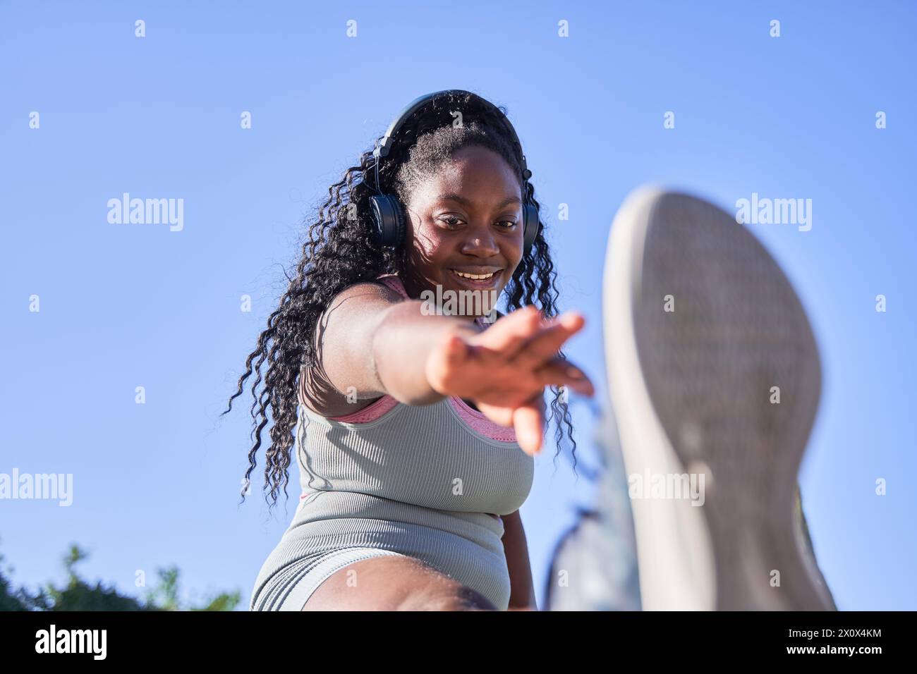 Junge afroamerikanische Frau, die ihre Beine zum Sport ausdehnt Stockfoto