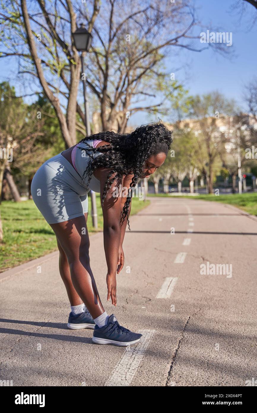 Kurvige Frau, die sich vor ihrem morgendlichen Workout ausdehnt. Junge afroamerikanerin, die sich trainiert. Stockfoto