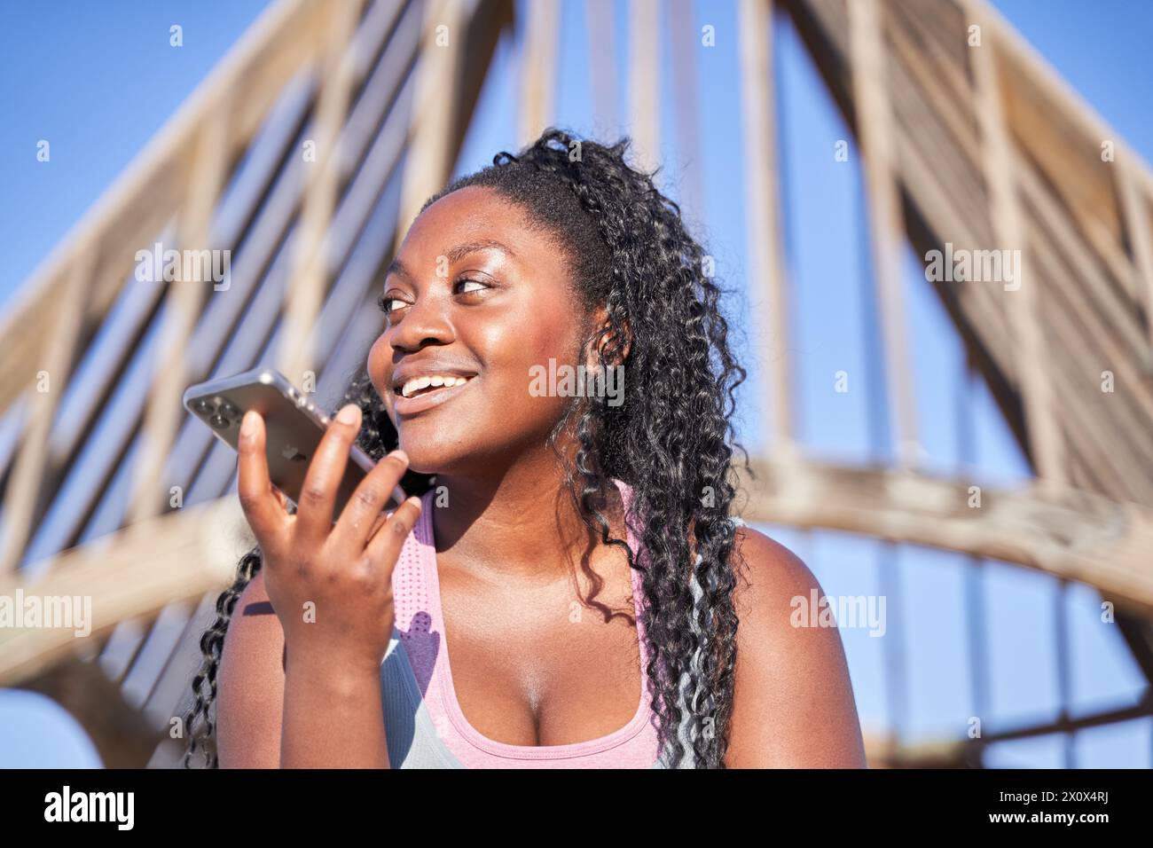 Glückliche junge afroamerikanische Frau, die mit der Spracherkennungs-App Audionachrichten auf dem Mobiltelefon aufnimmt und sendet. Gen Z Studentenmädchen gibt Befehl Stockfoto
