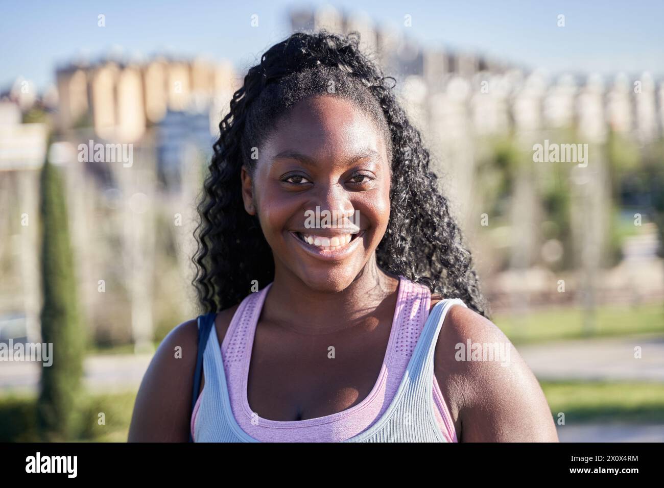 Porträt einer jungen afroamerikanischen Frau mit lockigen Haaren mit weißen Zähnen Stockfoto