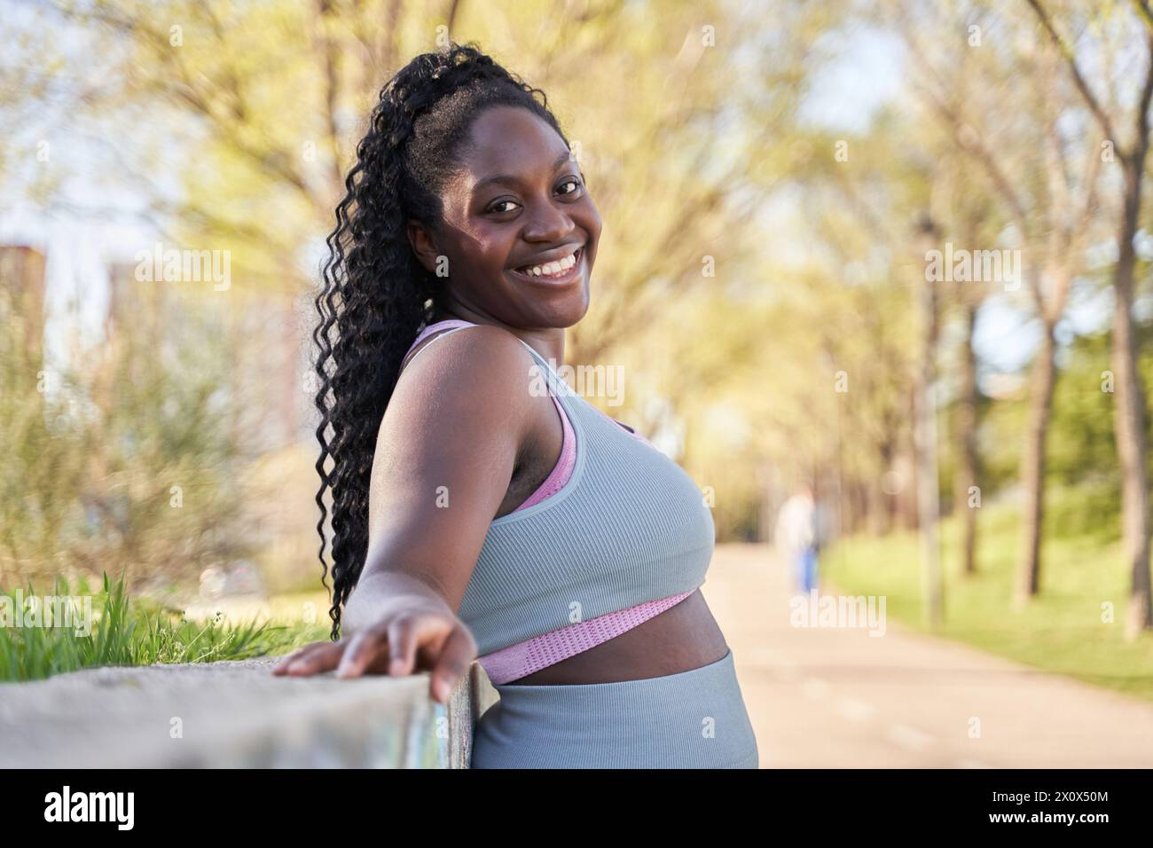 afroamerikanische Frau lehnt sich an eine Steinmauer und lächelt Stockfoto
