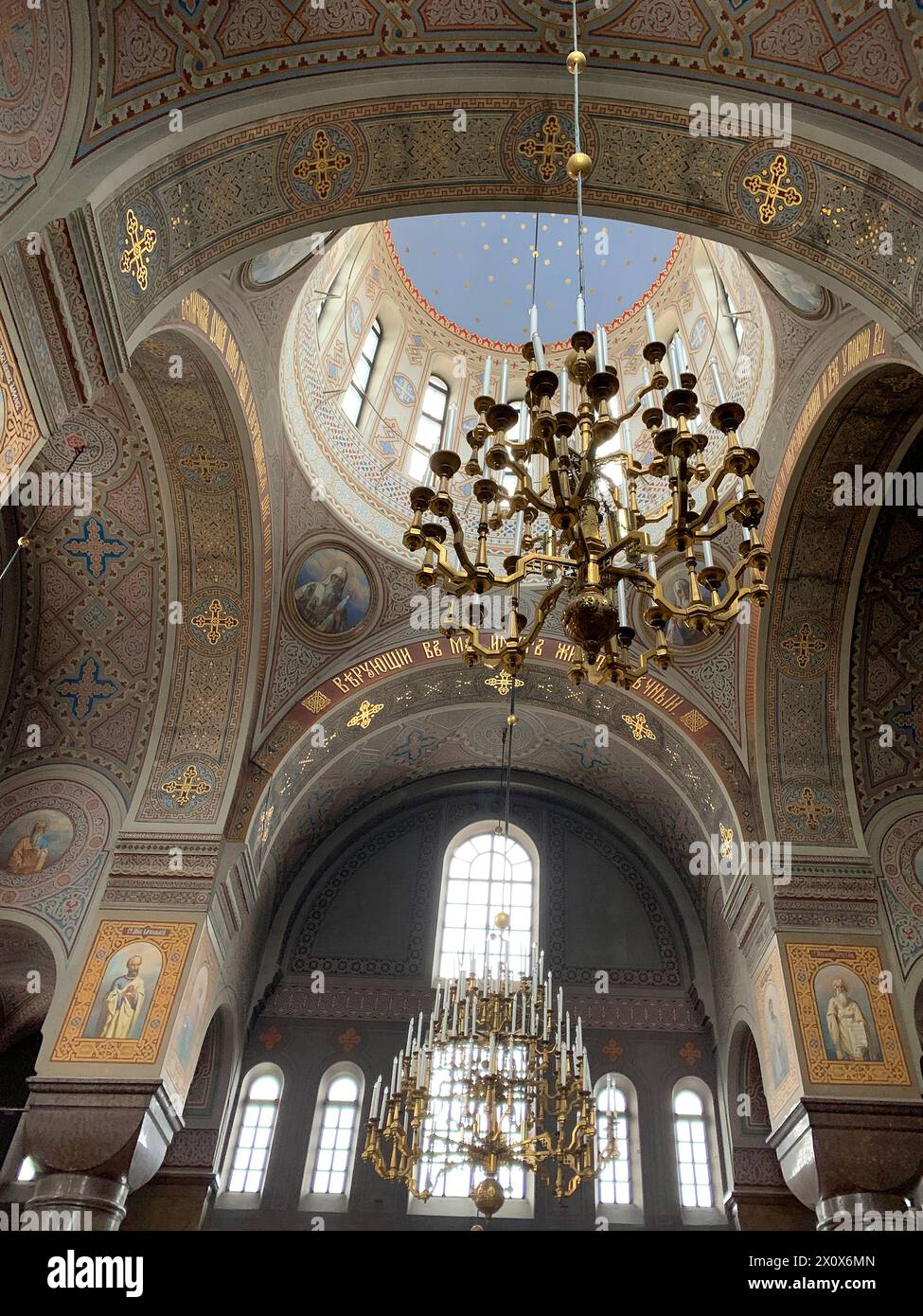 Traditionelles klassisches Kircheninnere mit Heiligenbildern, kunstvoll verzierten antiken Kronleuchtern mit Kerzen, religiöse Architektur, spirituelle Atmosphäre, Archi Stockfoto