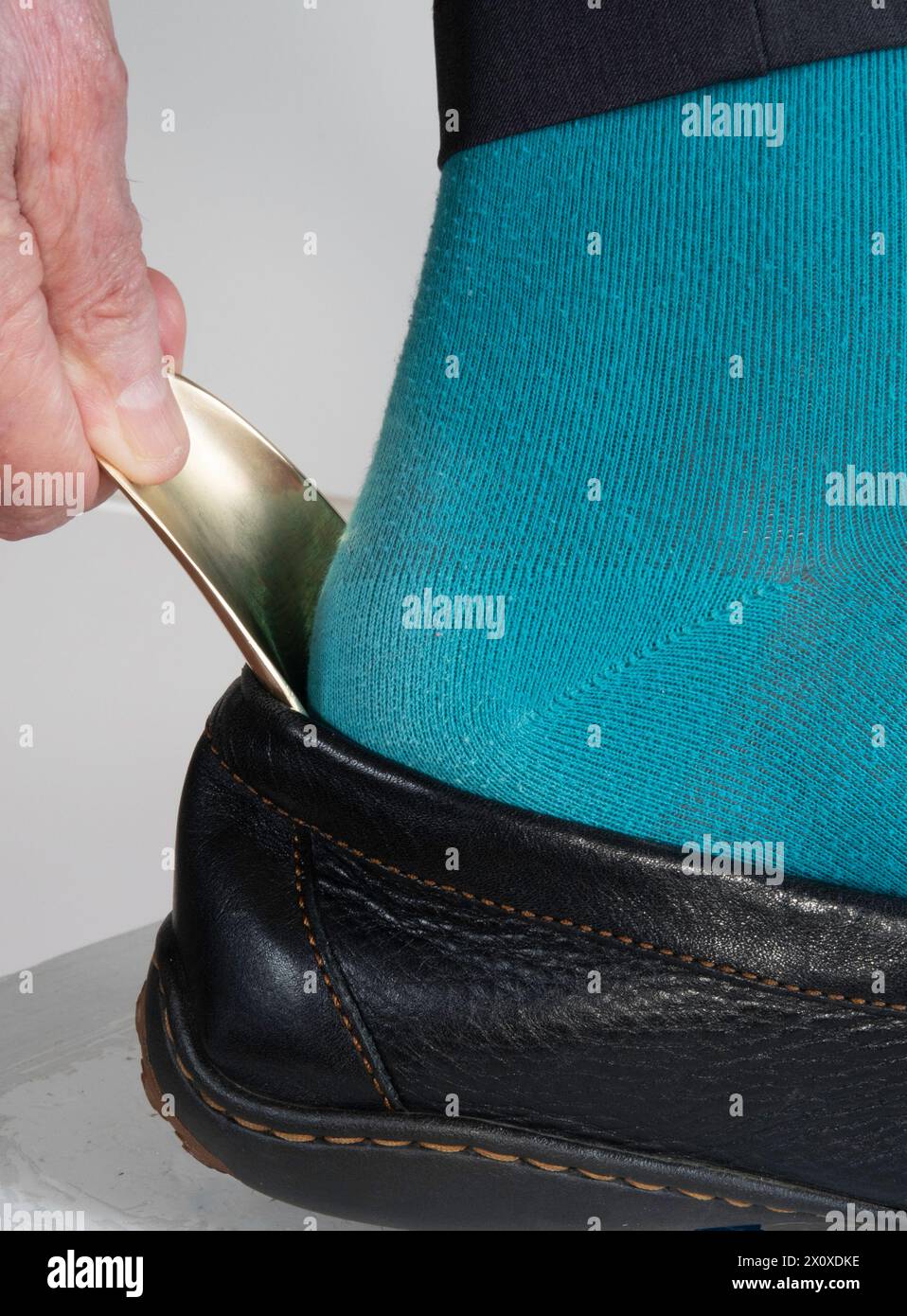 Reifer Mann benutzt ein Schuh, um seinen Fuß leicht in seinen Schuh zu schieben, 2024, USA Stockfoto