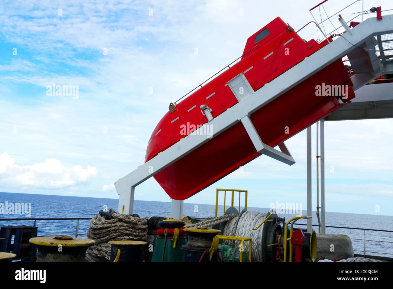 Orange Freifall Rettungsboot gesichert auf weißer Startrampe und bereit, Schiff mit Besatzung in Notsituationen zu starten und zu verlassen. Stockfoto