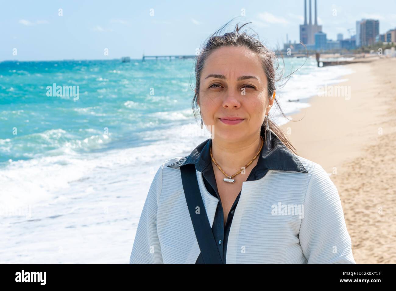 Straßenporträt einer glücklichen Frau 40-45 Jahre alt auf dem Hintergrund des Meeres und des Strandes. Stockfoto