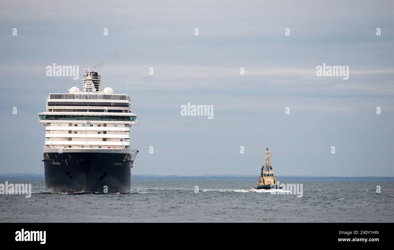 Dieses dynamische Stockbild zeigt eine Vorderansicht des Kreuzfahrtschiffs Zuiderdam, eines Schiffes der Holland America Line, begleitet von einem Pilotenschiff als navi Stockfoto