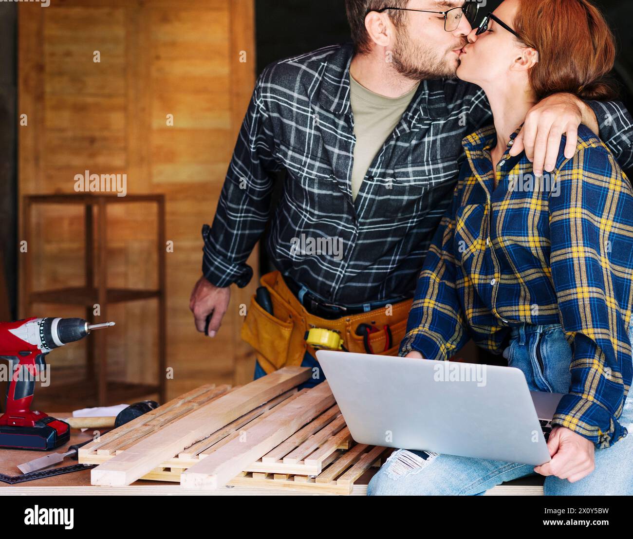 Familie, kleines lokales Geschäft und Feier Erfolg. Der Ehemann küsst seine Frau während der Arbeit in ihrer Werkstatt. Stockfoto