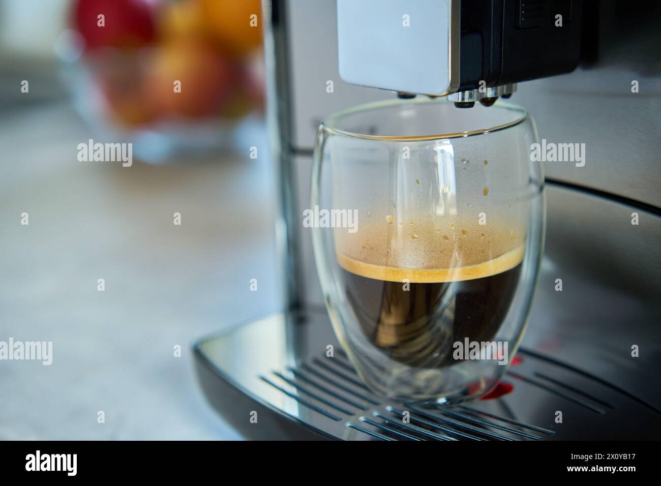 Frischer Espresso am Morgen. Kaffeemaschine in der Küche, Nahaufnahme. Moderne Kaffeemaschine mit frisch gebrühtem Kaffee in Glasbecher. Küchengeräte Stockfoto