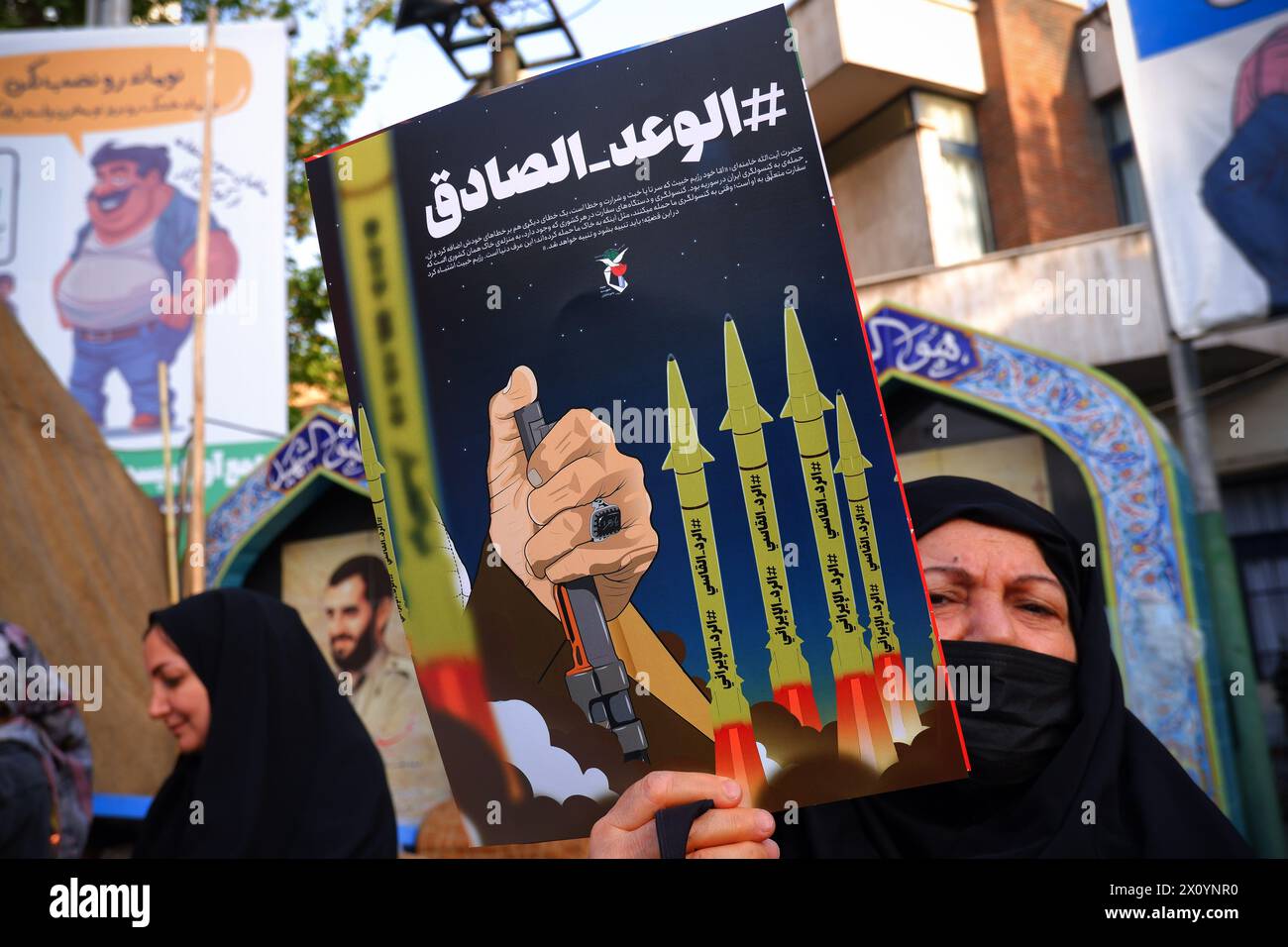 Teheran, Iran. April 2024. Eine regierungsnahe iranische Unterstützerin hält ein Anti-Israel-Poster auf der Palestine Street in der Innenstadt von Teheran. Israel feierte am Sonntag seine Luftverteidigung angesichts eines beispiellosen Angriffs des Iran und sagte, dass die Systeme 99 % der mehr als 300 Drohnen und Raketen, die auf sein Territorium abgefeuert wurden, vereitelten. (Kreditbild: © Rouzbeh Fouladi/ZUMA Press Wire) NUR REDAKTIONELLE VERWENDUNG! Nicht für kommerzielle ZWECKE! Stockfoto