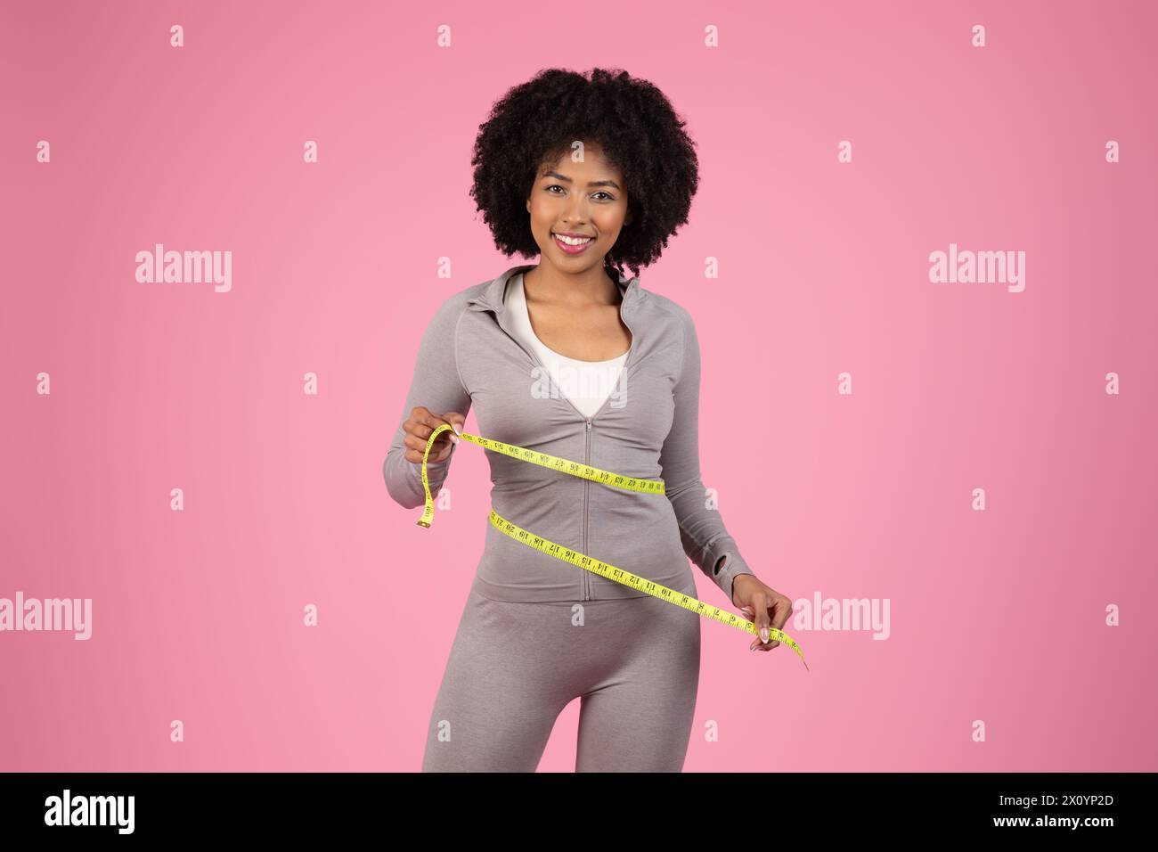 Glückliche Dame mit Maßband auf rosa Hintergrund Stockfoto
