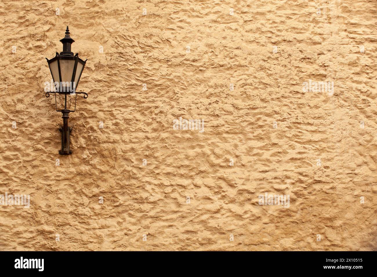 Eine alte schwarze Laterne mit Glas an der gelben rauen Wand eines Hauses in Tallinn. Estland. Horizontal Stockfoto