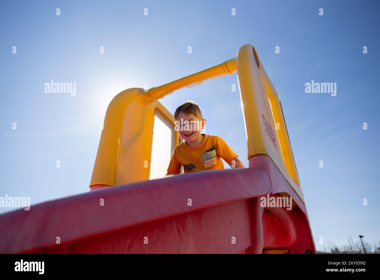 Ein kleiner Junge lacht oben auf einer Rutsche vor der Telus World of Science in Calgary Stockfoto