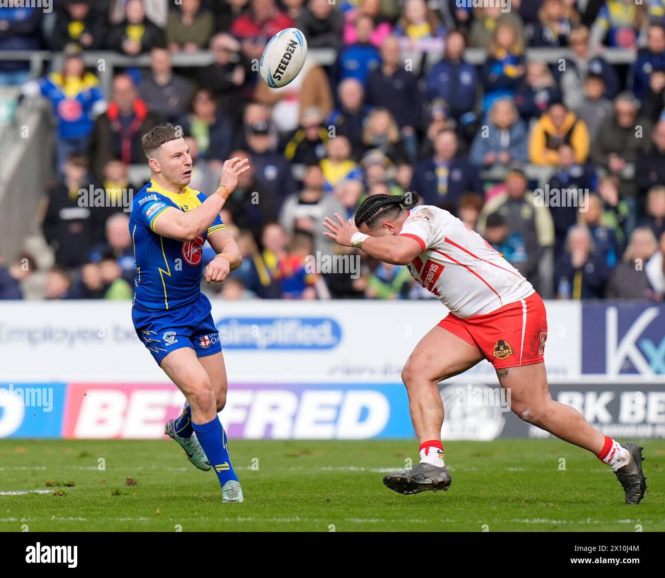 George Williams von Warrington Wolves wirft den Ball über Konrad Hurrell von St. Helens während des Viertelfinales des Betfred Challenge Cup St Helens gegen Warrington Wolves im Totally Wicked Stadium, St Helens, Großbritannien, 14. April 2024 (Foto: Steve Flynn/News Images) Stockfoto