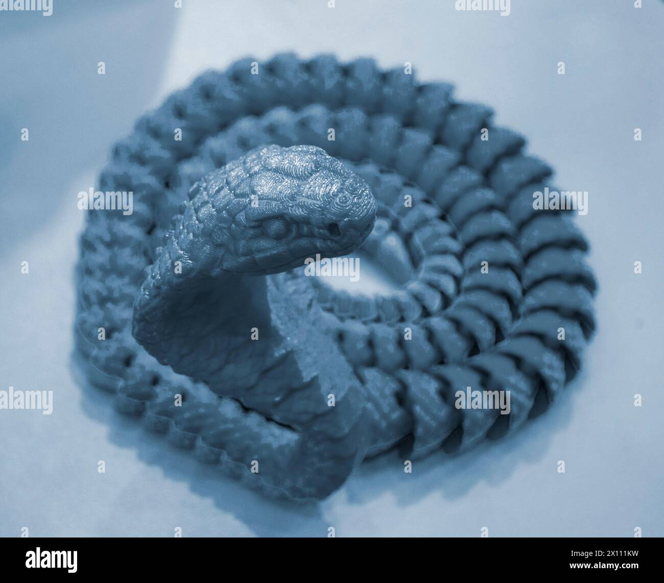 Schlangenspielzeugmodell, gedruckt auf einem 3D-Drucker aus geschmolzenem Kunststoff. Vom 3D-Drucker erzeugtes Objekt in Schlangenform. Detaillierter grüner Prototyp auf 3D-Drucker in Nahaufnahme gedruckt. Neue moderne Additivtechnologien Stockfoto