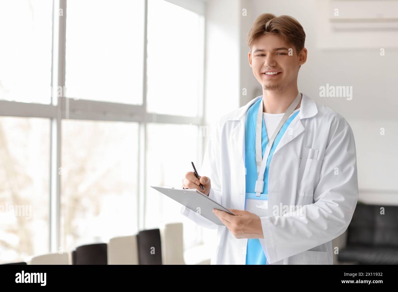 Männlicher Arzt mit Klemmbrett in Fensternähe in der Klinik Stockfoto