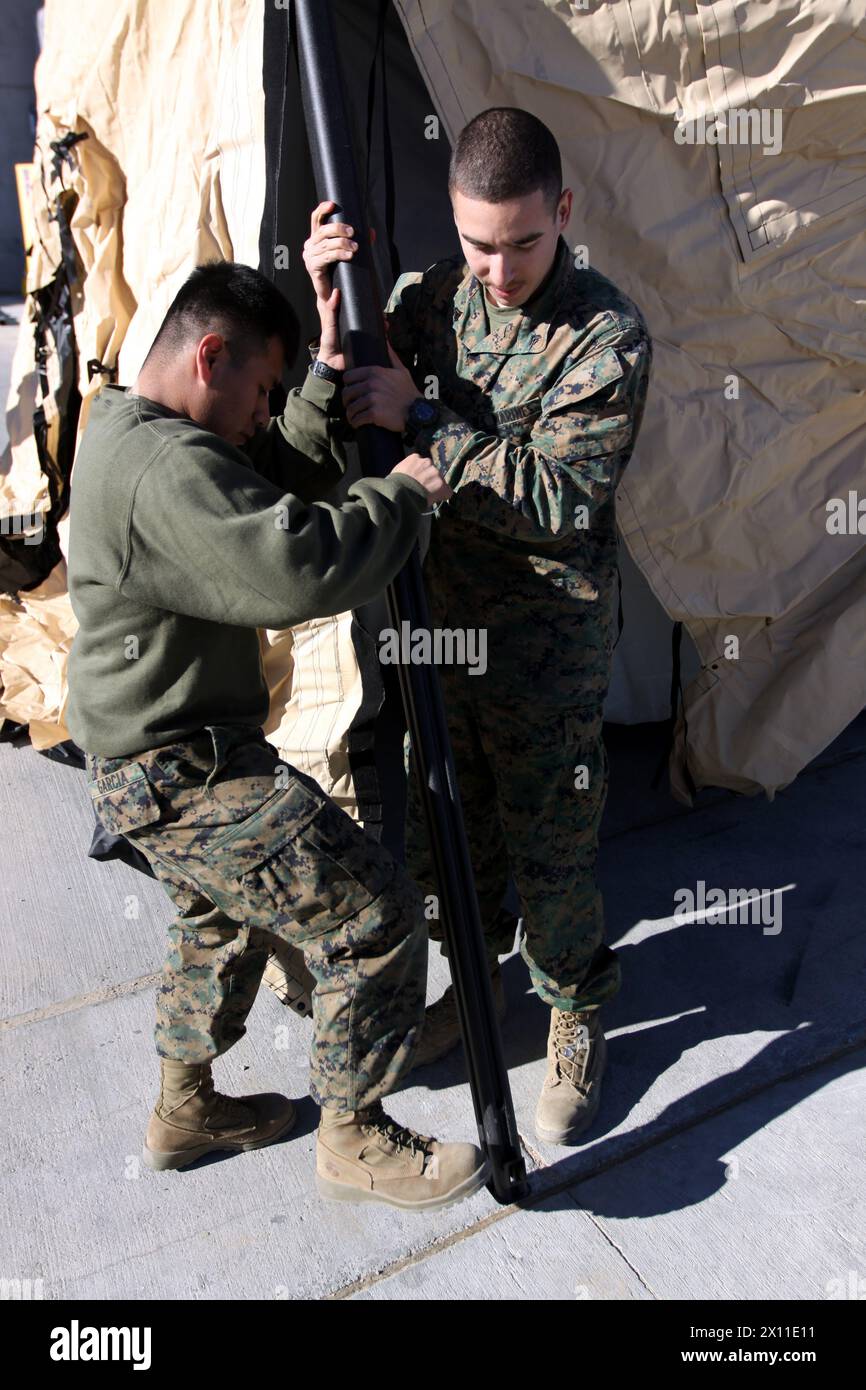 Victor E. Garcia (links), ein Lagerbeamter mit Hauptquartier und Service Company, 1. Panzerbataillon, und CPL. Cruz Salazar, ein Draht mit 1. Panzern, erweitern einen Stützbalken beim Aufbau des Rapid Deployment Sustem-480 Militärzelt im Versorgungslager des Bataillons am 14. Januar 2010. Stockfoto