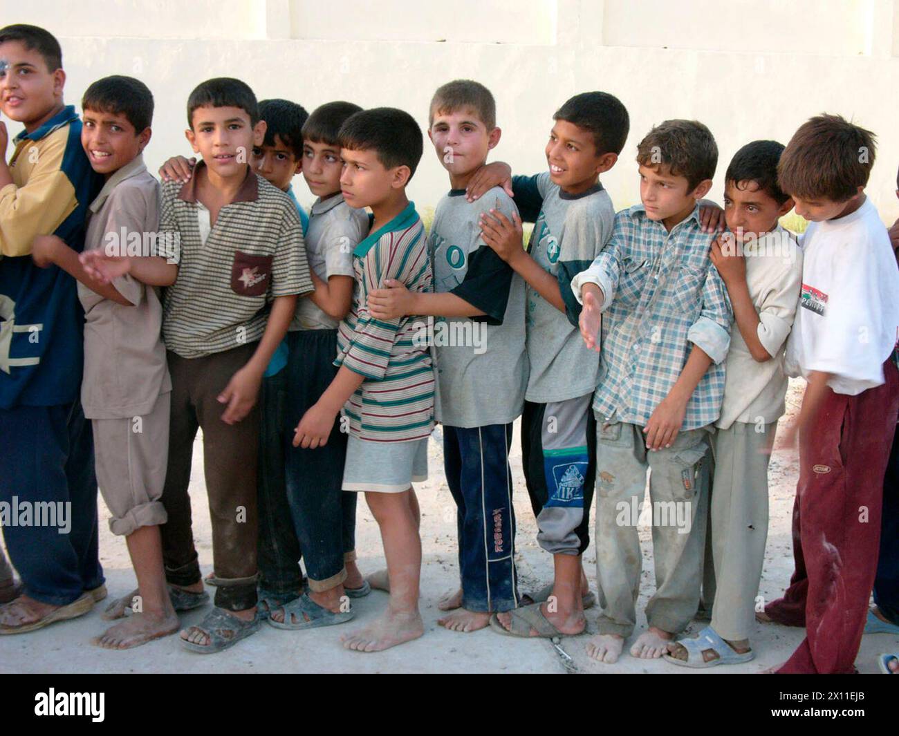 Während eines Karnevals, der vom 5. Brigade Combat Team CA veranstaltet wird, stehen die Kinder in einer geordneten Schlange, während sie auf ihre Rucksäcke und Schuhe warten. August 2004 Stockfoto