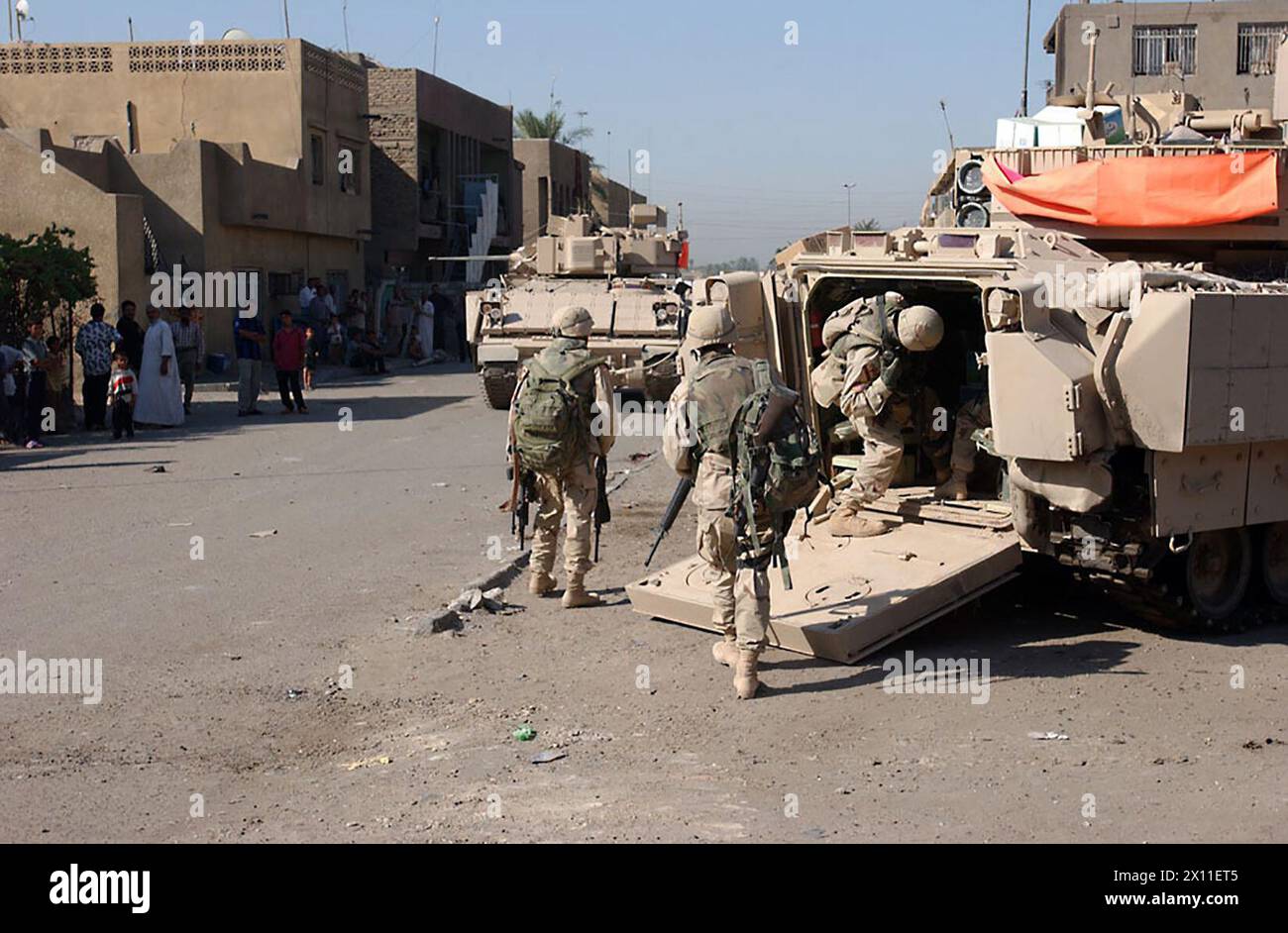 Soldaten Einer Kompanie, 2-5 Kavallerie, 1. Brigade Combat Team, 1. Kavalleriedivision montieren ein Bradley Kampffahrzeug, nachdem sie am 27. August weitere Gebäude in der Gegend durchsucht haben. Als Teil der Task Force Lancer nahmen Soldaten von 2-5 Cav an der Operation Iron Fury Teil, die die Straßen von Sadr City für zivile Militäroperationen CA sicher machen sollte. August 2004 Stockfoto