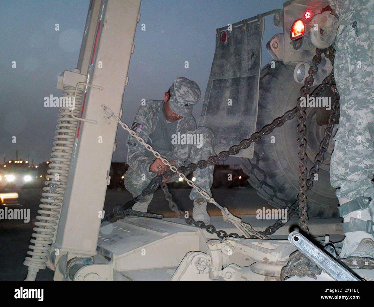 Ein Betreiber schwerer Radfahrzeuge der 2101st Transportation Company, 394th Combat Sustainment Support Battalion, 3rd Sustainment Brigade, 103rd Sustainment Command (Expeditionary) auf der Joint Base Balad Iraq, verstärkt eine Ladung auf den MCT-Bahnen, bevor die Mission ausgeht. Juli 2004 Stockfoto
